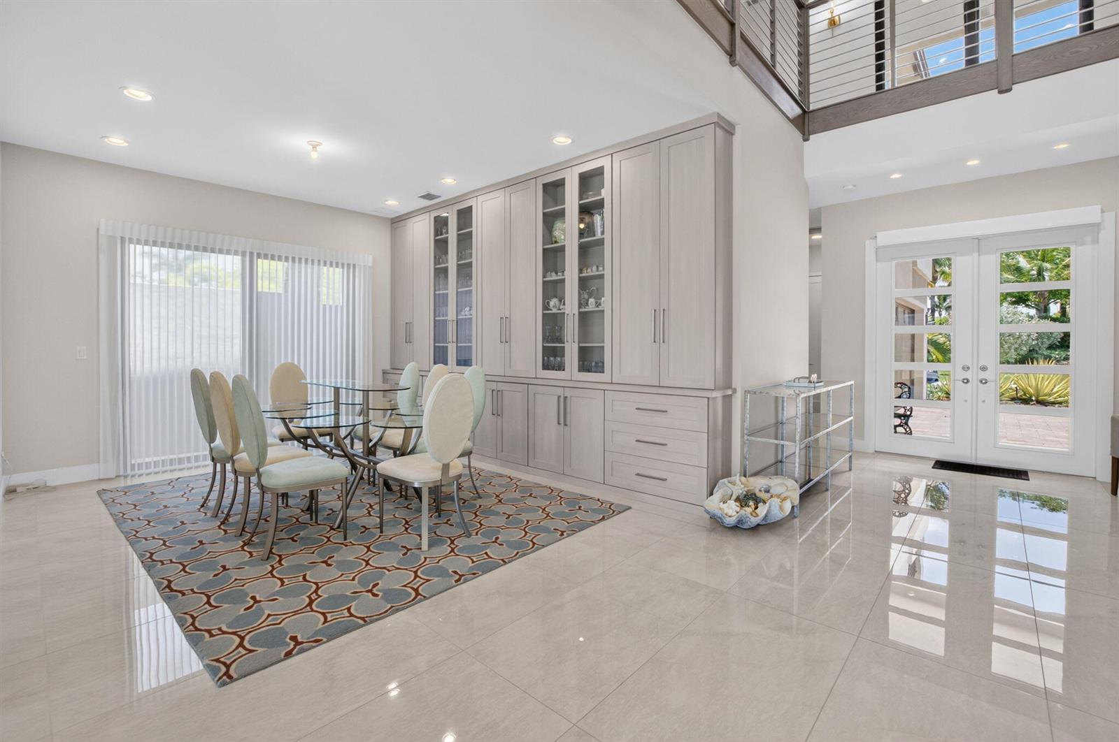 A dining area features a glass table, patterned rug, and floor-to-ceiling light-toned cabinetry — 17100 Wandering Wave Avenue, Boca Raton FL 33496, BOCA RATON, FL