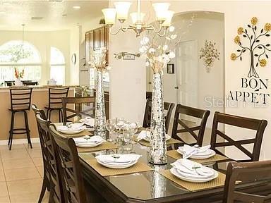 A dining room features a glass table, dark wood chairs, and a decorative wall decal — 1010 TOURMALINE DRIVE, KISSIMMEE, FL