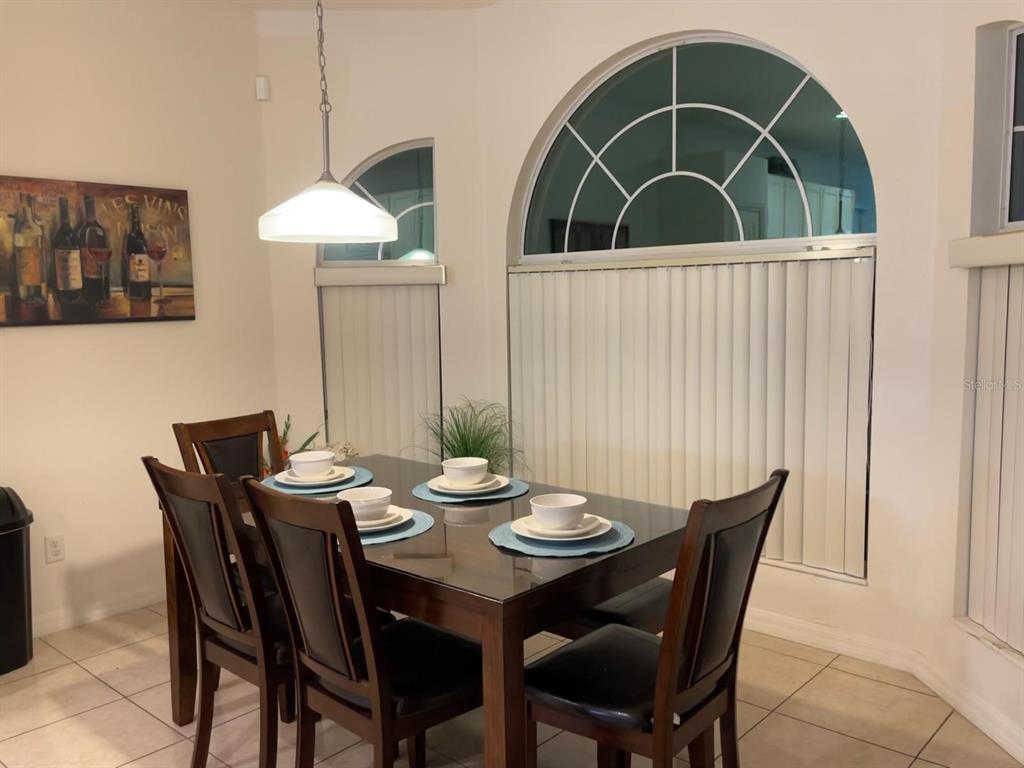 A dining room features a dark wood table with place settings and a large arched window — 1010 TOURMALINE DRIVE, KISSIMMEE, FL