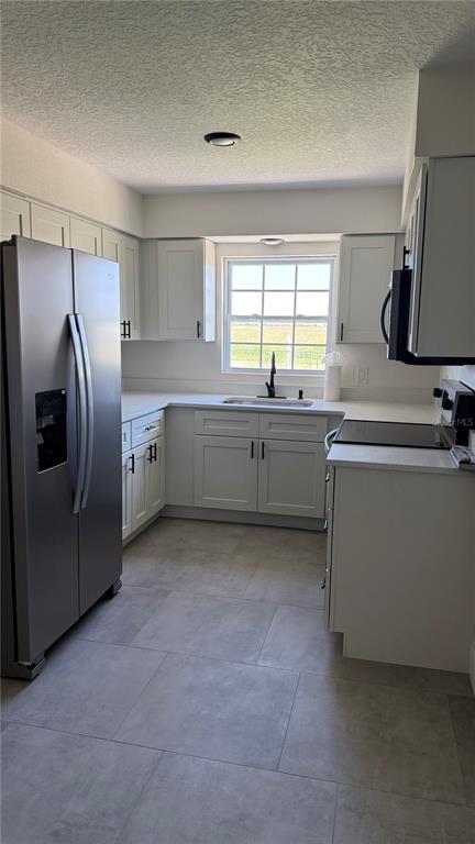 A kitchen features white cabinets, stainless steel appliances, a window, and light gray tile flooring — 606 RIDGEWOOD AVENUE, DUNDEE, FL