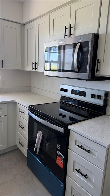 A kitchen features white cabinets, stainless steel appliances, and light-colored countertops — 606 RIDGEWOOD AVENUE, DUNDEE, FL