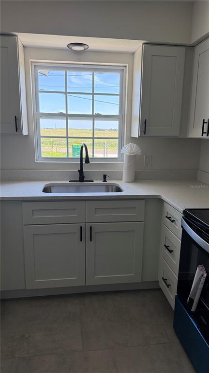 A kitchen features white cabinets, a stainless steel sink, a black faucet, and a window — 606 RIDGEWOOD AVENUE, DUNDEE, FL