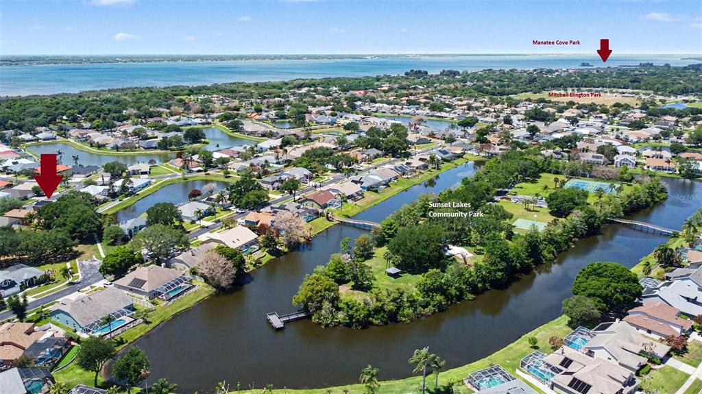 This aerial view shows a residential neighborhood with lakes, green spaces, and a nearby bay — 3621 TIPPERARY DRIVE, MERRITT ISLAND, FL