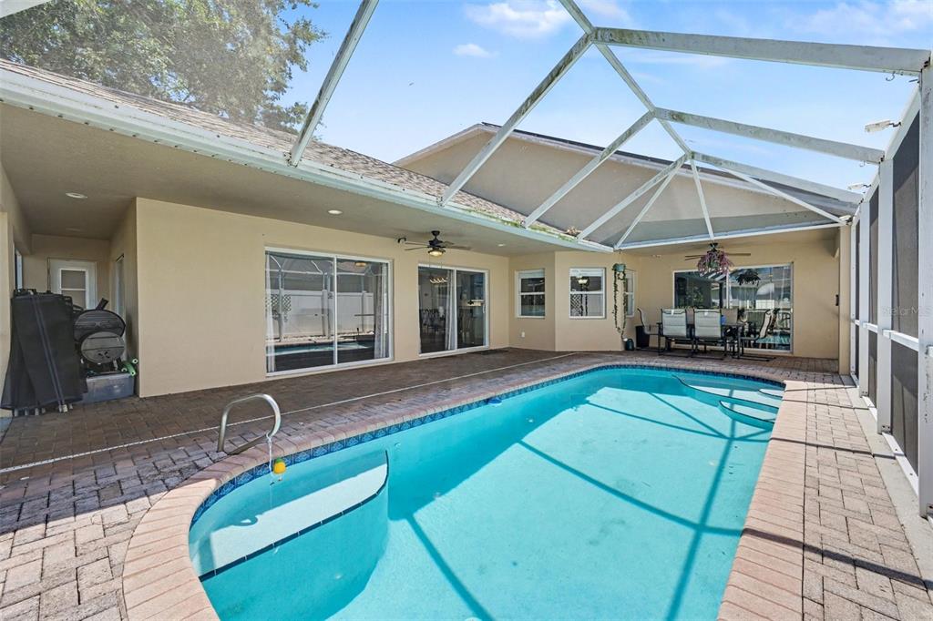 A screened-in patio features a swimming pool with a built-in step and brick pavers — 3621 TIPPERARY DRIVE, MERRITT ISLAND, FL