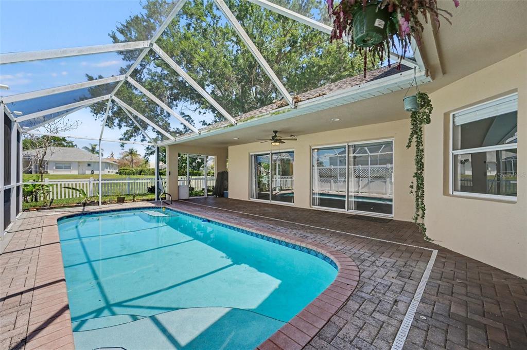 A screened-in patio features a swimming pool, brick pavers, and sliding glass doors — 3621 TIPPERARY DRIVE, MERRITT ISLAND, FL