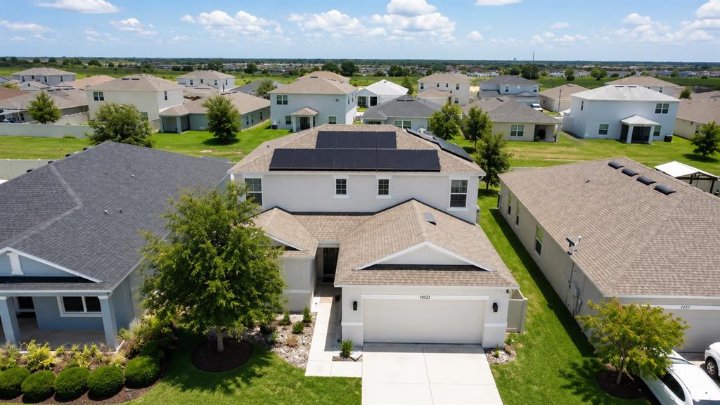 An aerial view shows a two-story house with solar panels on the roof — 5225 TUSCANY LANE, DAVENPORT, FL
