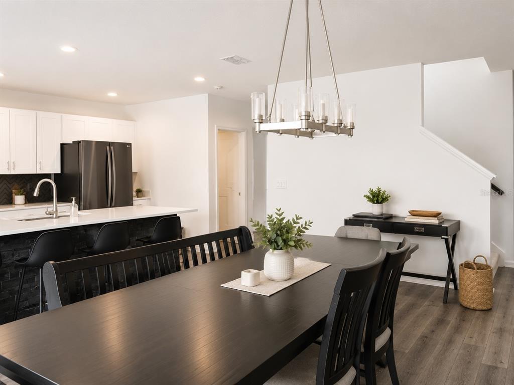 A dining area with a dark wood table and chairs sits beside a modern kitchen — 5225 TUSCANY LANE, DAVENPORT, FL