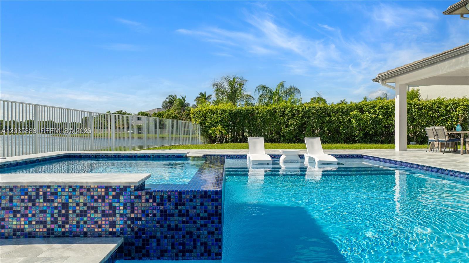 A swimming pool with a tiled spa and two lounge chairs sits on a patio — 2505 Hunters Run Way, Weston FL 33327, WESTON, FL