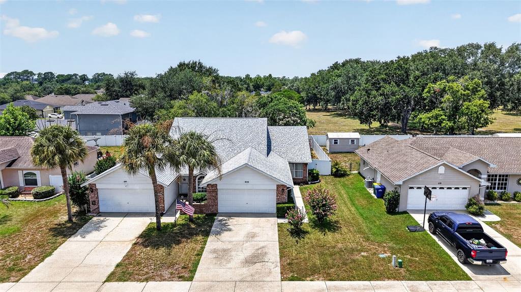 An aerial view shows a suburban house with a two-car garage and a blue truck — 626 WOODVIEW DRIVE, TAVARES, FL