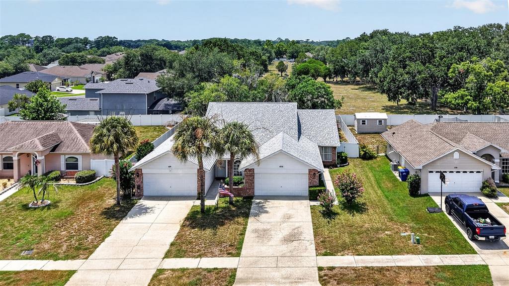 An aerial view shows a single-story duplex house with two garages and palm trees — 626 WOODVIEW DRIVE, TAVARES, FL