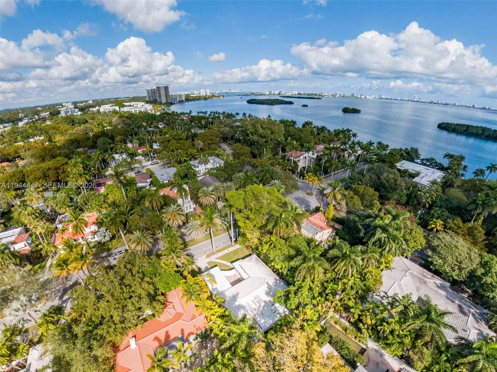 An aerial view shows a lush, tree-filled residential neighborhood situated along a large bay — 680 NE 57th St, Miami FL 33137, MIAMI, FL