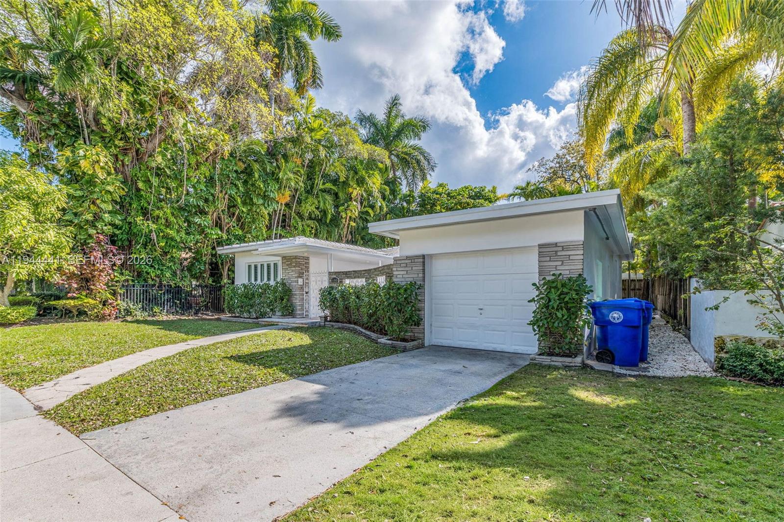 A single-story house with a white garage, stone accents, and a concrete driveway — 680 NE 57th St, Miami FL 33137, MIAMI, FL