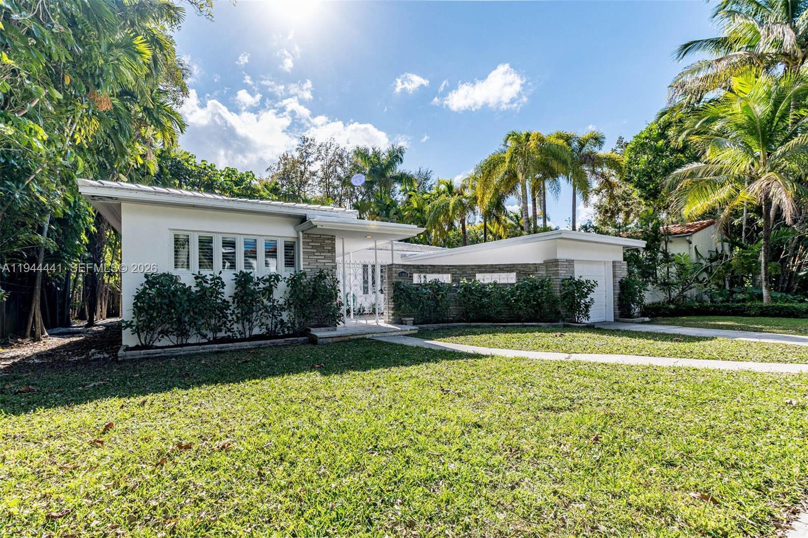 A single-story house with a flat roof, stone accents, and a front lawn with palms — 680 NE 57th St, Miami FL 33137, MIAMI, FL