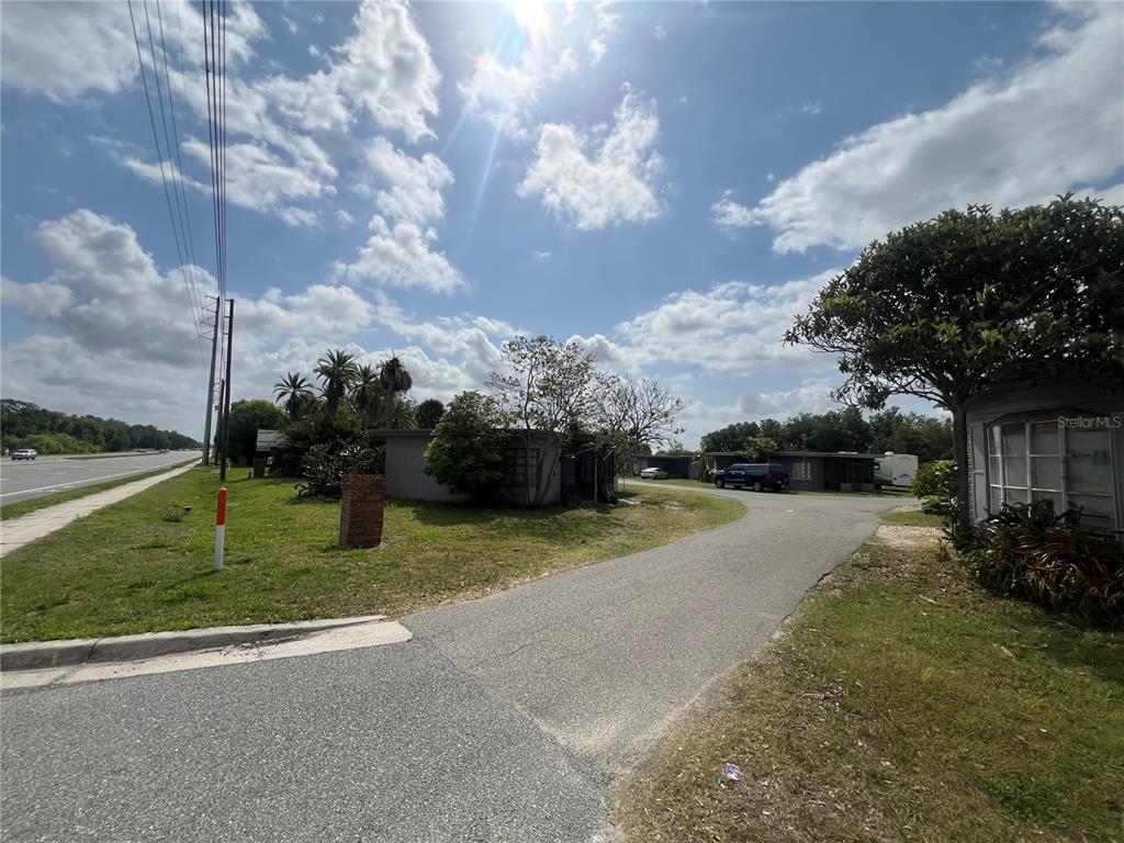 A paved driveway leads to a small house near a road under a sunny sky — 15992 W COLONIAL DRIVE, OAKLAND, FL