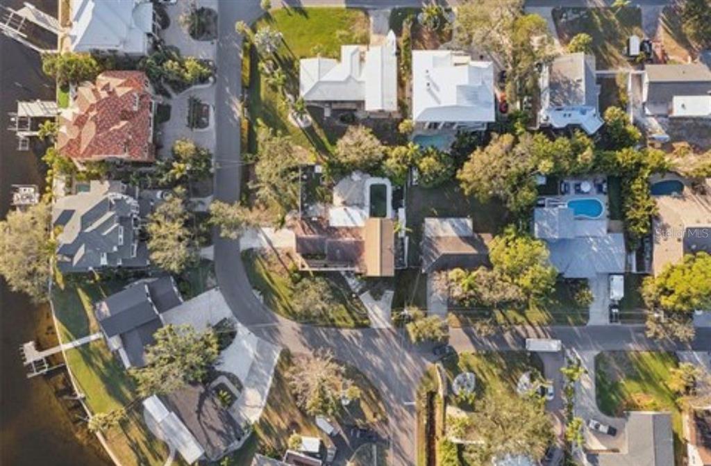 An aerial view shows several residential houses with pools and driveways near a waterfront — 100 AUGUSTA AVENUE, PALM HARBOR, FL