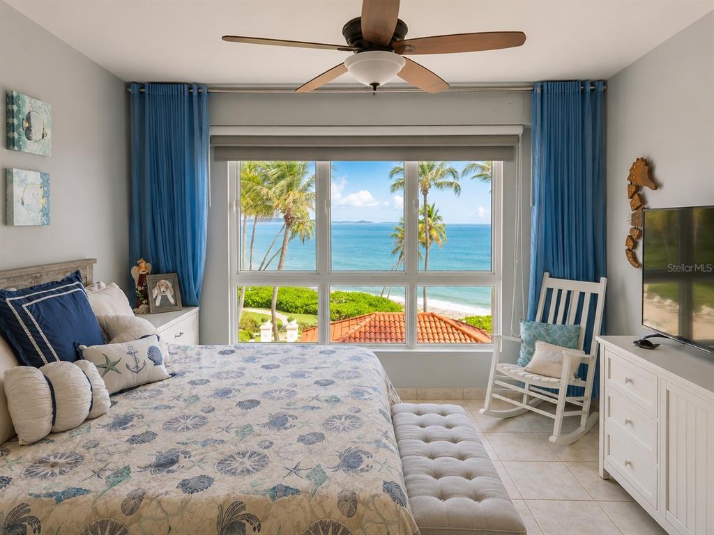 A bedroom features a bed, a rocking chair, and a large window overlooking the ocean — 200 OCEAN DRIVE UNIT 231, HUMACAO, PR