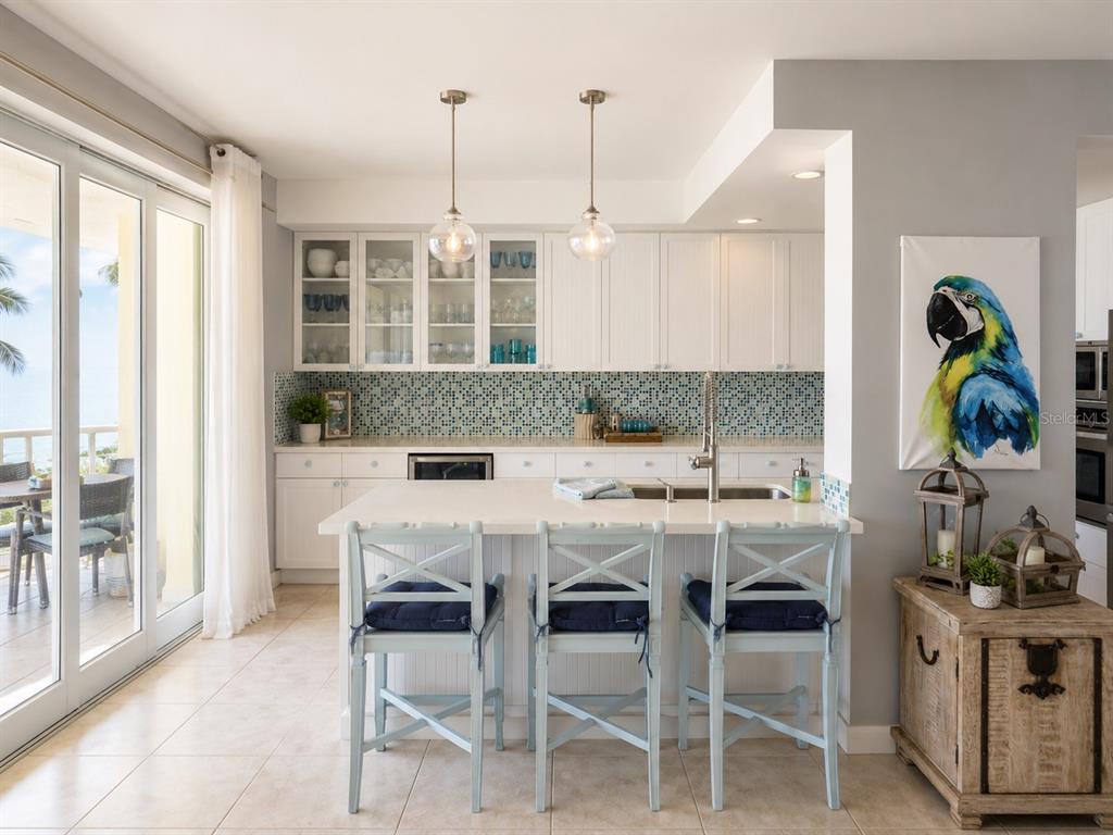 A kitchen with white cabinets, a blue mosaic backsplash, a center island, and bar stools — 200 OCEAN DRIVE UNIT 231, HUMACAO, PR