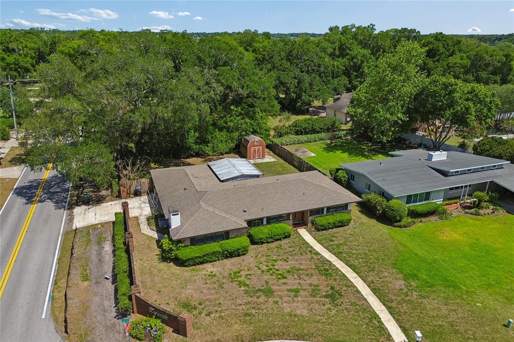 A large, grassy backyard features mature oak trees, a gazebo, and a view of water — 4801 BIG OAKS LANE, ORLANDO, FL