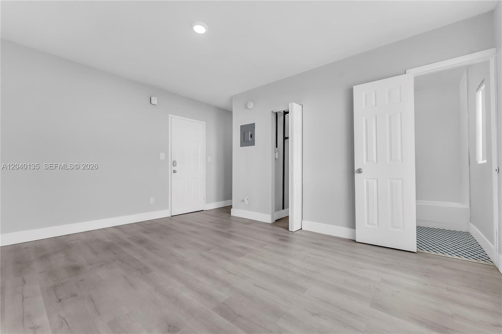 A room with light gray walls, wood-look flooring, a closet, and an open bathroom door — 6647 SW 59th Pl # 207, South Miami FL 33143, SOUTH MIAMI, FL