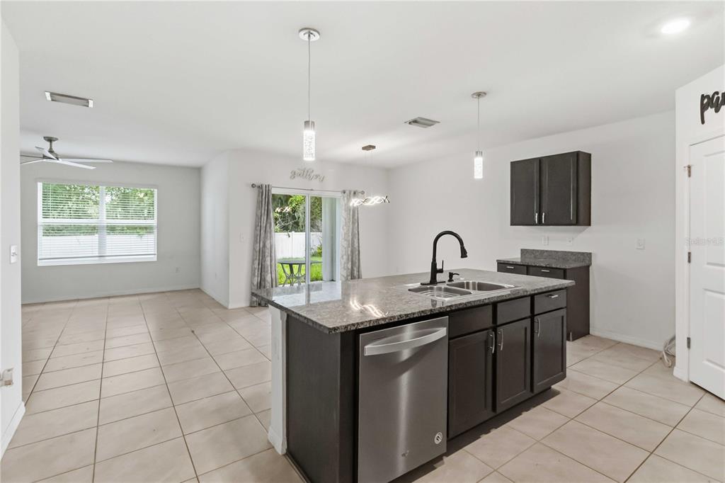A kitchen features dark wood cabinets, granite countertops, a center island, and a pantry door — 1702 JOHNSON POINTE DRIVE, PLANT CITY, FL