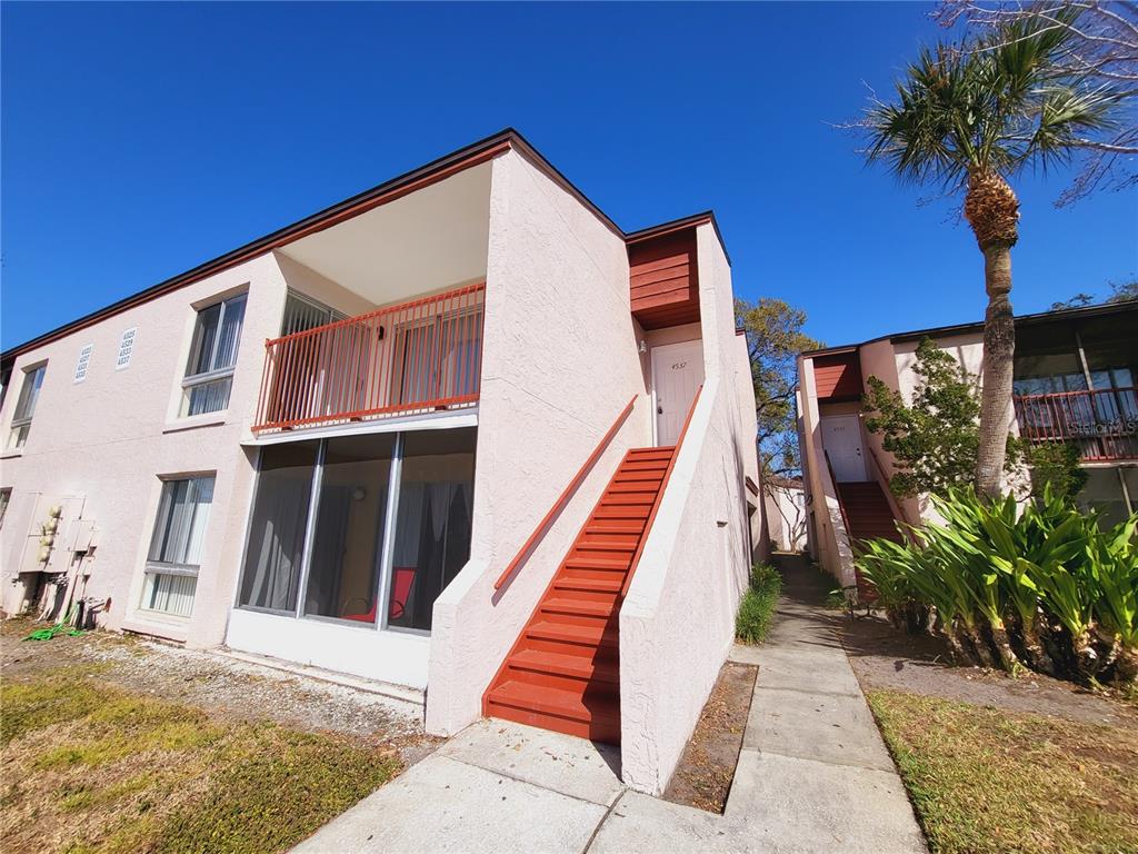 A two-story pink stucco apartment building with exterior stairs and a screened-in ground floor patio — 4537 LAKEWAY DRIVE UNIT 3706, ORLANDO, FL