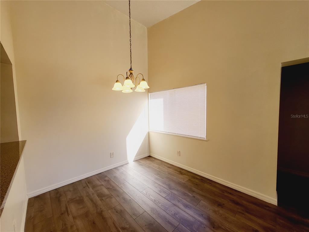 A dining area with wood-look flooring, a vaulted ceiling, and a hanging light fixture — 4537 LAKEWAY DRIVE UNIT 3706, ORLANDO, FL