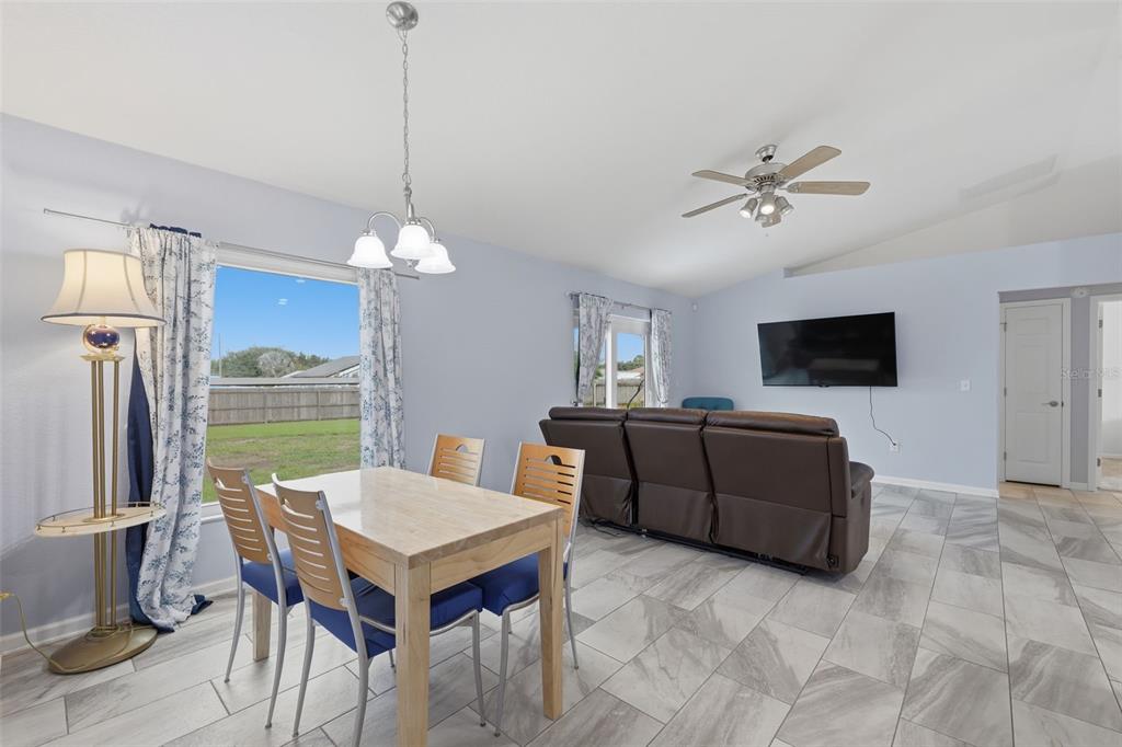 A dining area with a wooden table and chairs opens into a living room with tile — 1233 MERRIMACK DRIVE, DAVENPORT, FL