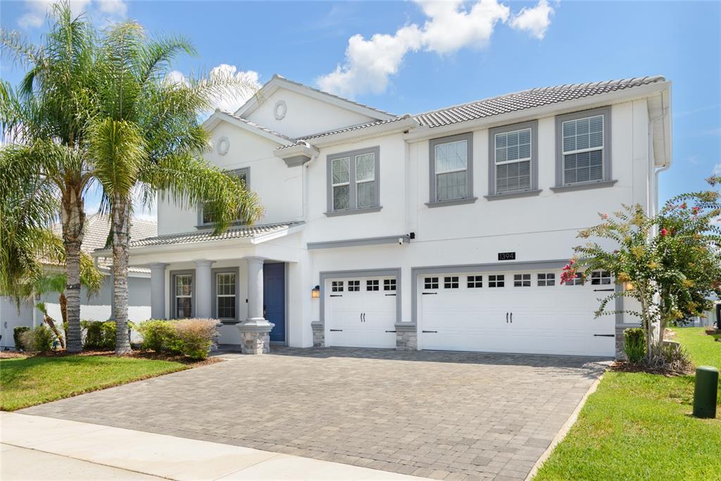A two-story white house with a paver driveway and a three-car garage — 1394 OLYMPIC CLUB BOULEVARD, CHAMPIONS GATE, FL