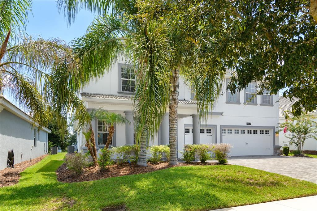 A two-story white house with a garage, palm trees, and a paved driveway — 1394 OLYMPIC CLUB BOULEVARD, CHAMPIONS GATE, FL