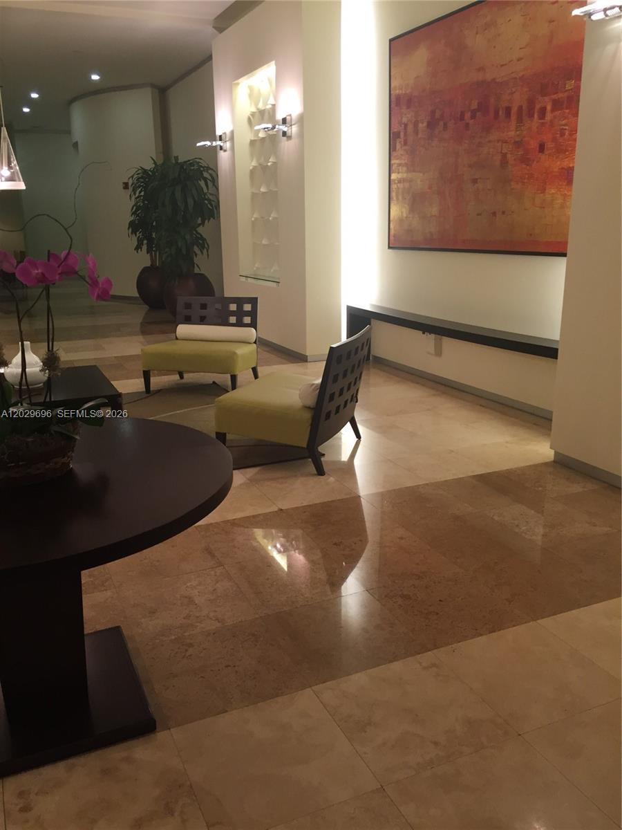 A modern lobby features light-colored tile floors, two lime-green chairs, and a large abstract painting — 9066 SW 73rd Ct # 907, Miami FL 33156, MIAMI, FL
