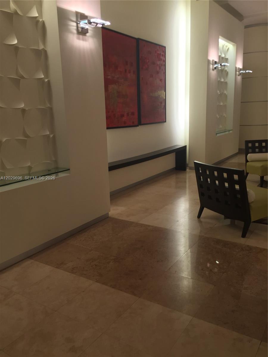 A modern lobby features tiled floors, a long console table, and two large red paintings — 9066 SW 73rd Ct # 907, Miami FL 33156, MIAMI, FL