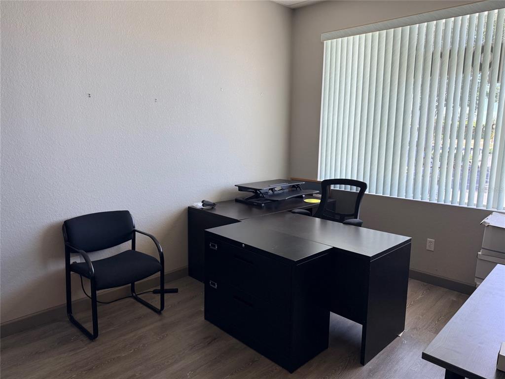An office space features a black L-shaped desk, a rolling chair, and a guest chair — 20020 VETERANS BOULEVARD UNIT 14, PORT CHARLOTTE, FL