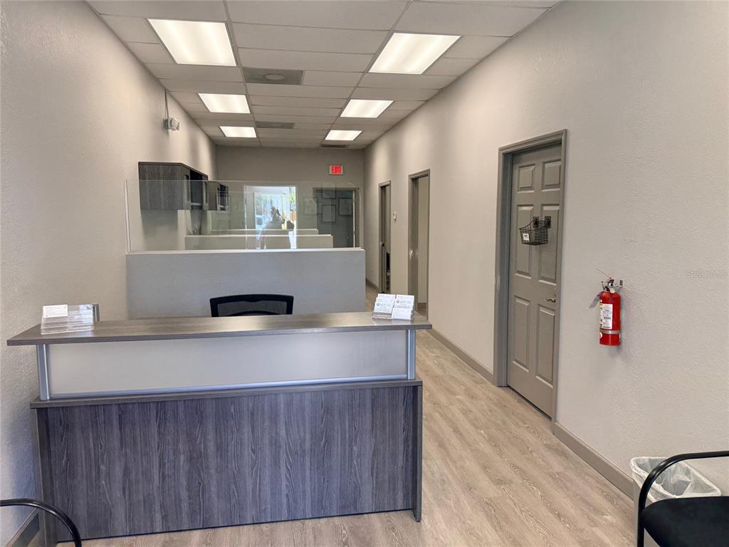 A reception desk sits in a commercial office space with light wood flooring and gray doors — 20020 VETERANS BOULEVARD UNIT 14, PORT CHARLOTTE, FL