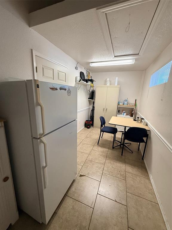 A kitchen area features a white refrigerator, a small table with two chairs, and tile flooring — 20020 VETERANS BOULEVARD UNIT 14, PORT CHARLOTTE, FL