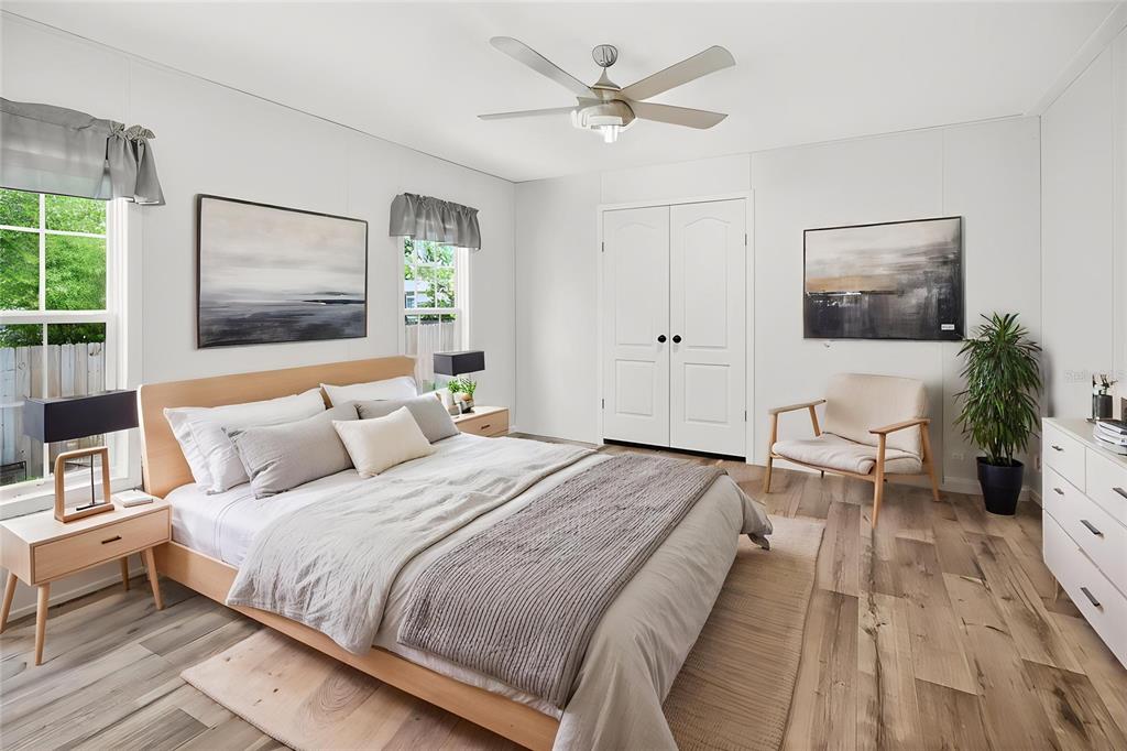 A bedroom features a wooden bed frame, light wood flooring, white walls, and a ceiling fan — 17475 TAVERN ROAD, BROOKSVILLE, FL