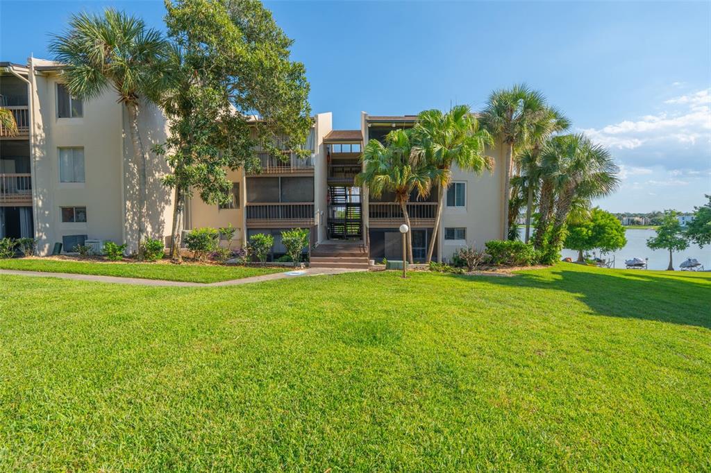 A multi-story apartment building with screened balconies sits behind a large, grassy lawn — 574 ORANGE DRIVE UNIT 76, ALTAMONTE SPRINGS, FL
