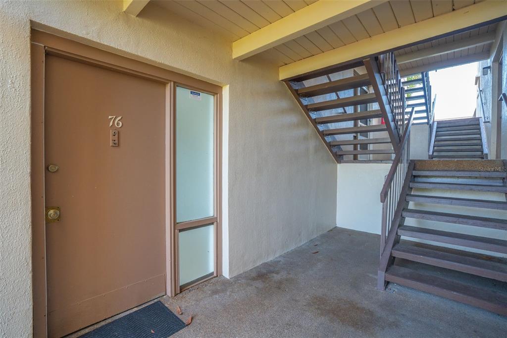 A brown front door with the number 76 next to an outdoor staircase — 574 ORANGE DRIVE UNIT 76, ALTAMONTE SPRINGS, FL