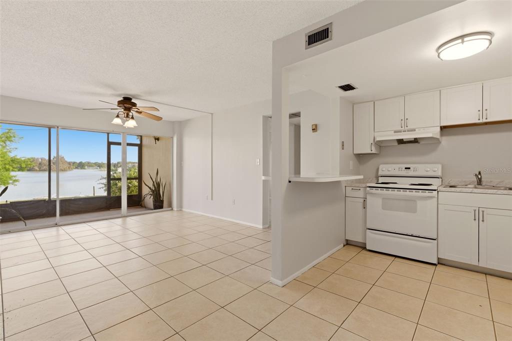 An open-concept kitchen and dining area with tile flooring and a view of a lake — 574 ORANGE DRIVE UNIT 76, ALTAMONTE SPRINGS, FL