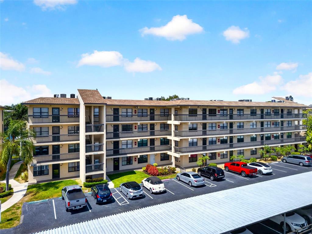 An exterior view of a multi-story apartment building with a parking lot in front — 505 30TH AVENUE W UNIT E303, BRADENTON, FL