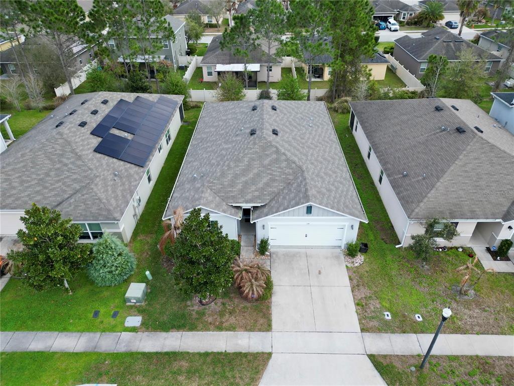 An aerial view shows three suburban houses with gray roofs and driveways on a residential street — 1141 AUGUSTUS DRIVE, DAVENPORT, FL