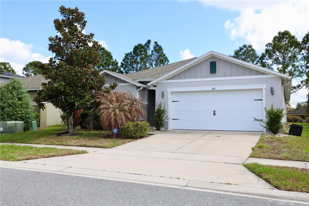 An aerial view shows three suburban houses with gray shingled roofs and concrete driveways — 1141 AUGUSTUS DRIVE, DAVENPORT, FL