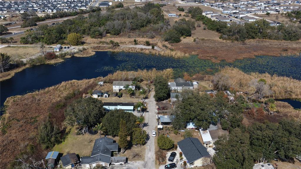 An aerial view shows several houses situated along a road near a large pond — 800 US HIGHWAY 17 92 S, DAVENPORT, FL