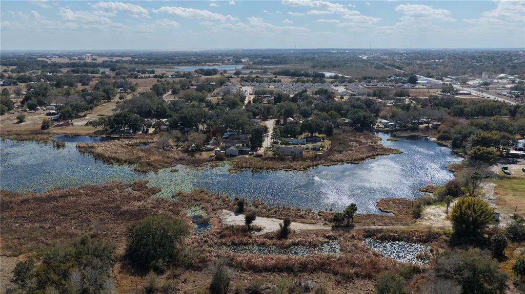 An aerial view shows a lake with lily pads surrounded by trees and residential houses — 800 US HIGHWAY 17 92 S, DAVENPORT, FL