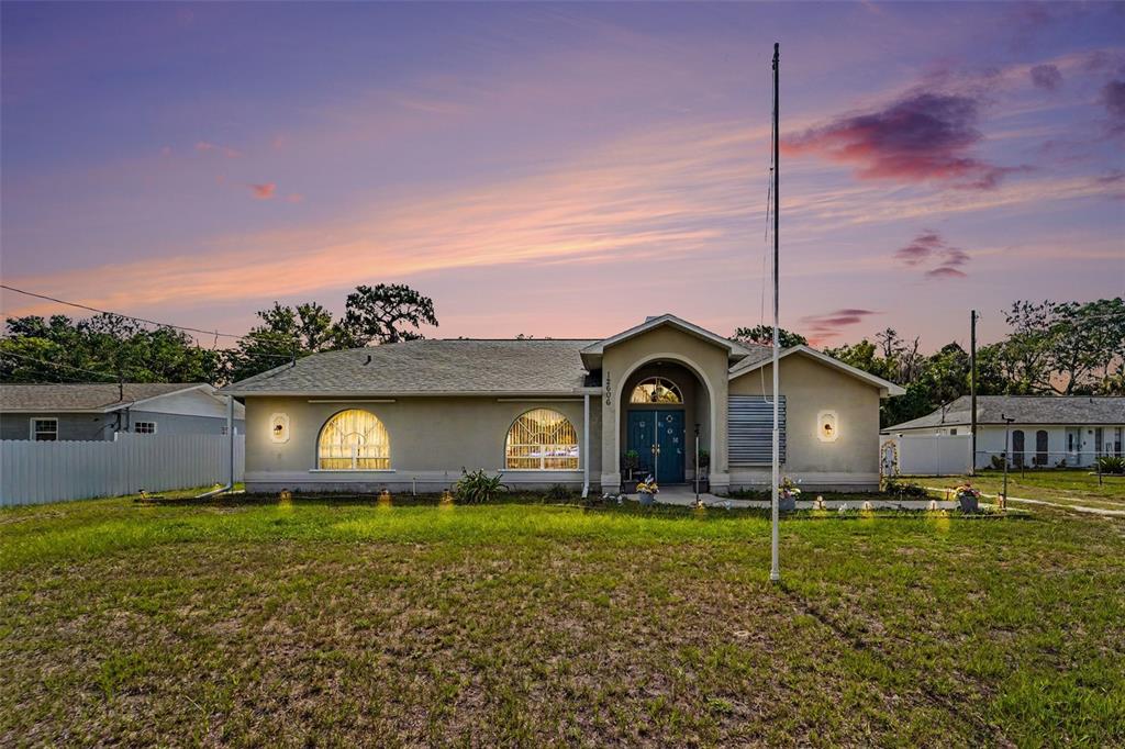 A single-story house with a beige stucco exterior, arched windows, and a central entryway — 12606 LITEWOOD DR, HUDSON, FL