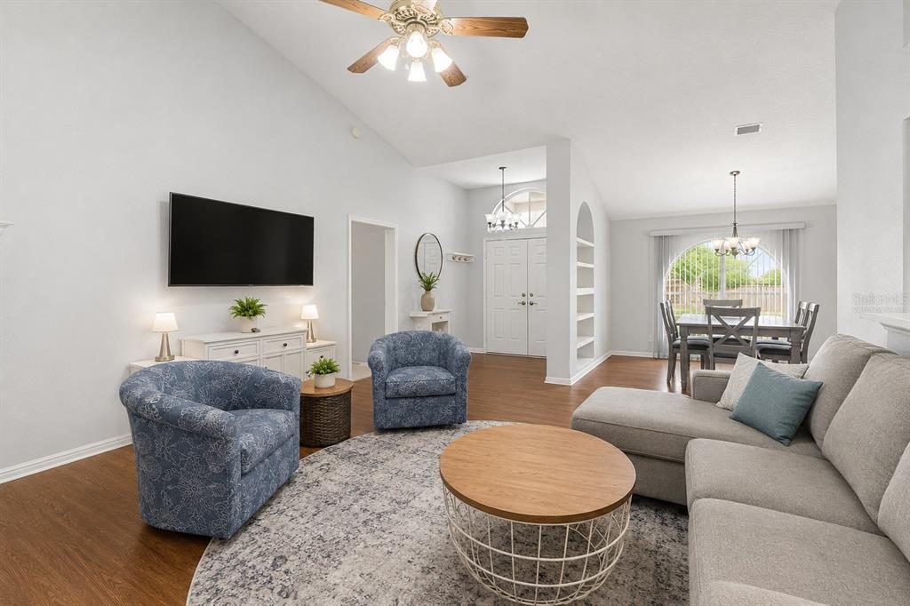 A living room with a gray sectional, two blue patterned armchairs, and wood flooring — 12606 LITEWOOD DR, HUDSON, FL