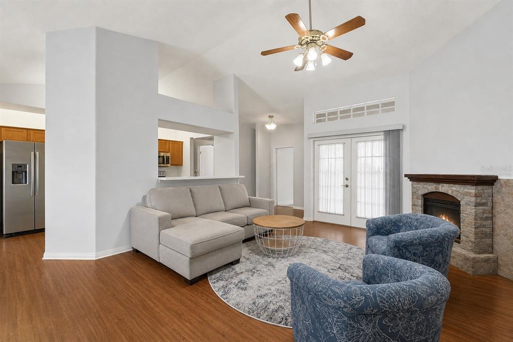 A living room with wood floors, a sectional sofa, two armchairs, and a stone fireplace — 12606 LITEWOOD DR, HUDSON, FL