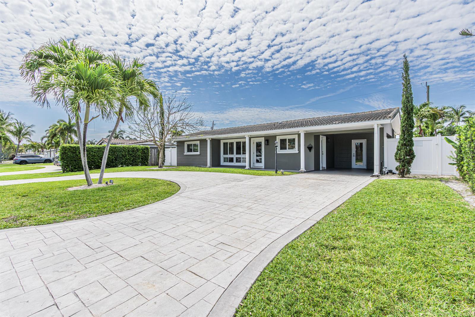 A gray single-story house features a paved circular driveway, white columns, and a palm tree — 2770 NE 53rd Street, Lighthouse Point FL 33064, LIGHTHOUSE POINT, FL