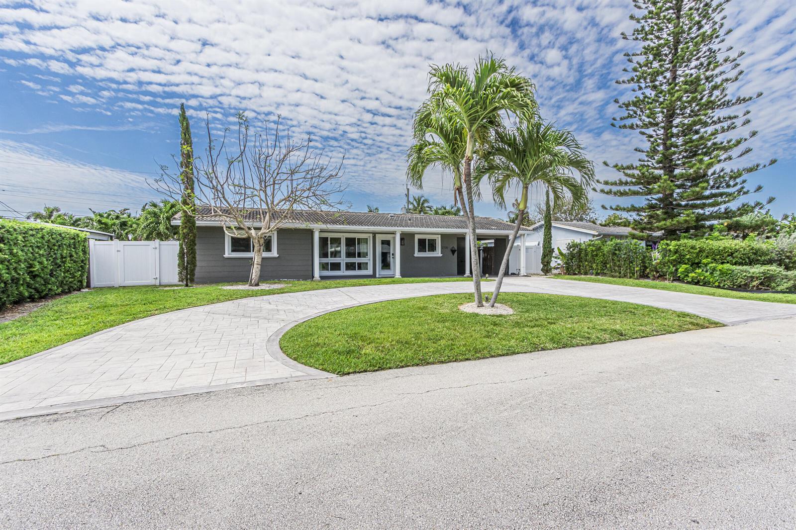 A gray single-story house features a circular paver driveway and a front lawn with palms — 2770 NE 53rd Street, Lighthouse Point FL 33064, LIGHTHOUSE POINT, FL