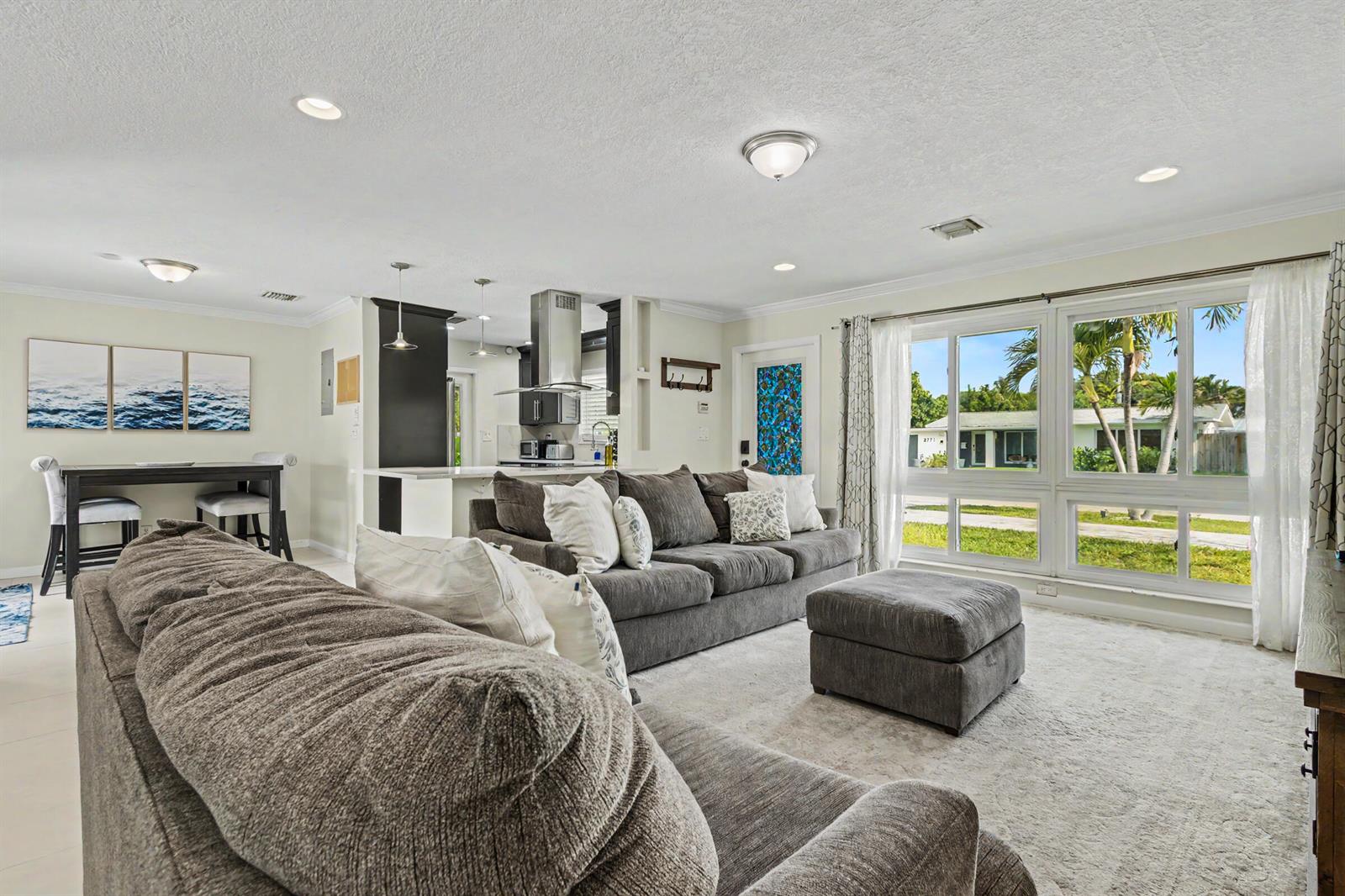 A living room with a grey sectional sofa, dining area, and large windows overlooking outdoors — 2770 NE 53rd Street, Lighthouse Point FL 33064, LIGHTHOUSE POINT, FL