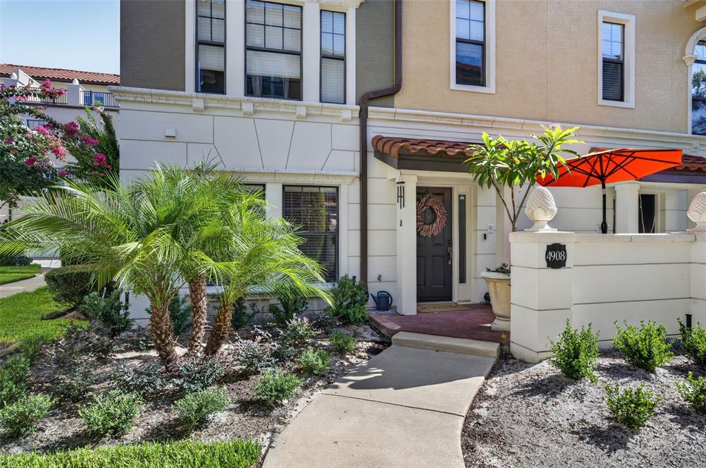 A multi-story townhouse exterior features a front walkway, a palm tree, and a patio umbrella — 4908 SAN MARINO CIRCLE, LAKE MARY, FL